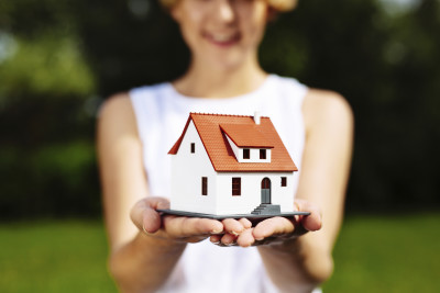 Photo of a young woman holding a miniature house